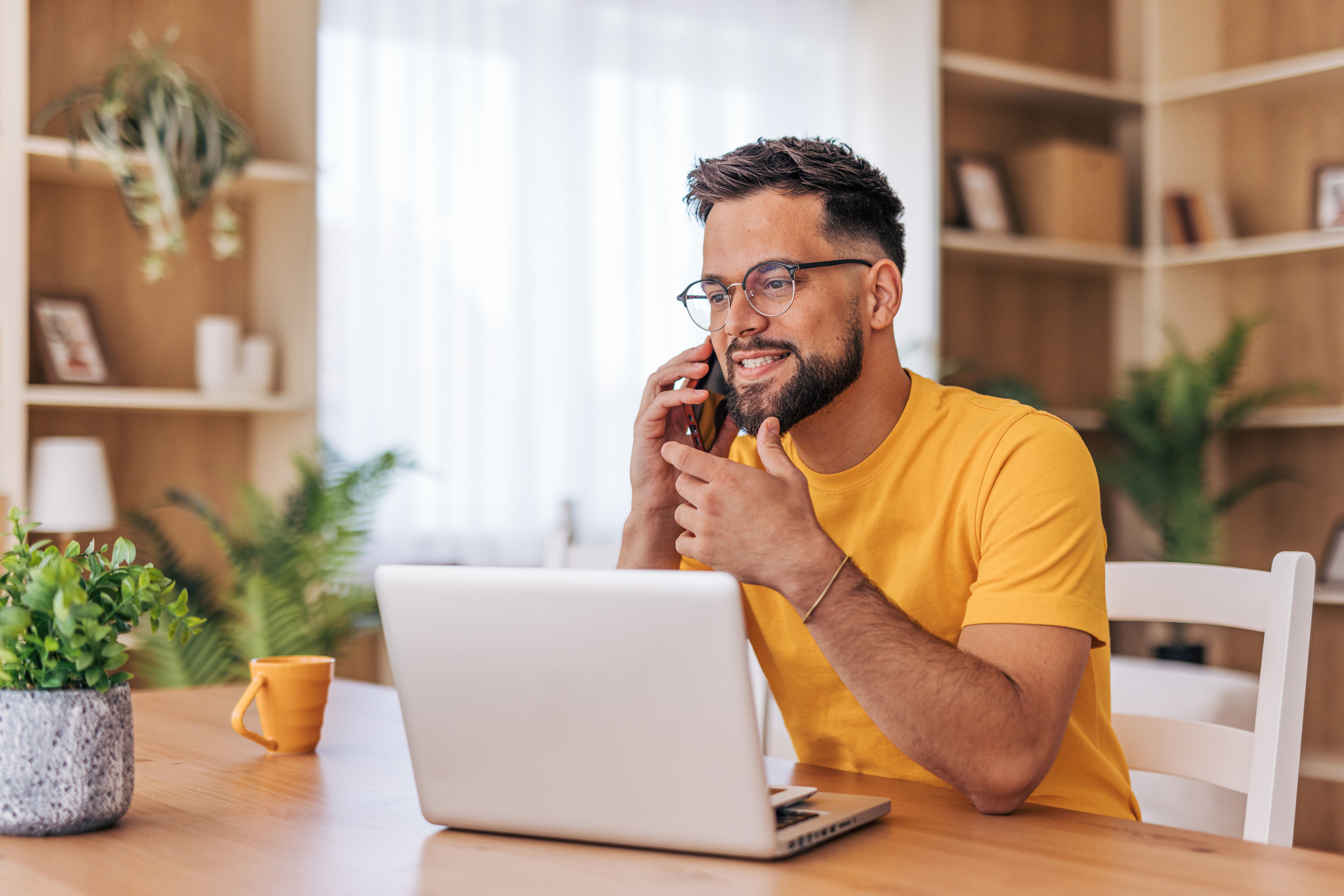 a man wearing a yellow t-shirt working on a laptop